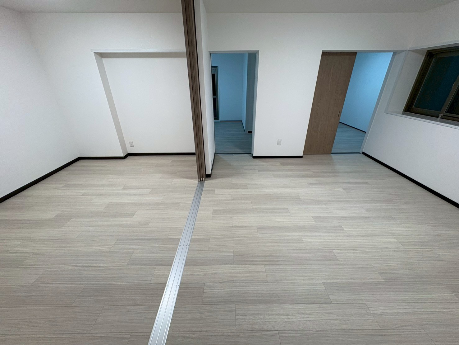 明るい木目調のフローリングが広がる、リフォーム済みの洋室。